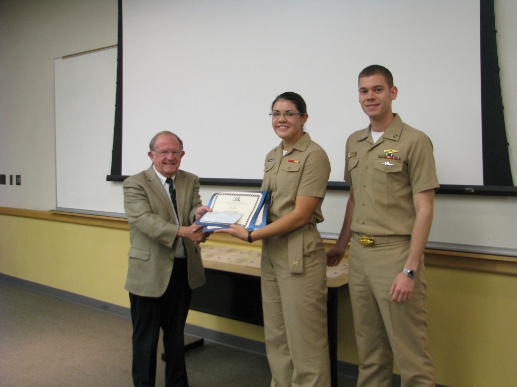 University of Idaho Dean of Students, Dr. Bruce Pittman, present MIDN Diana Vaught her award with Seapower & Maritime Affairs course instructor LT Nathan Greenwood.